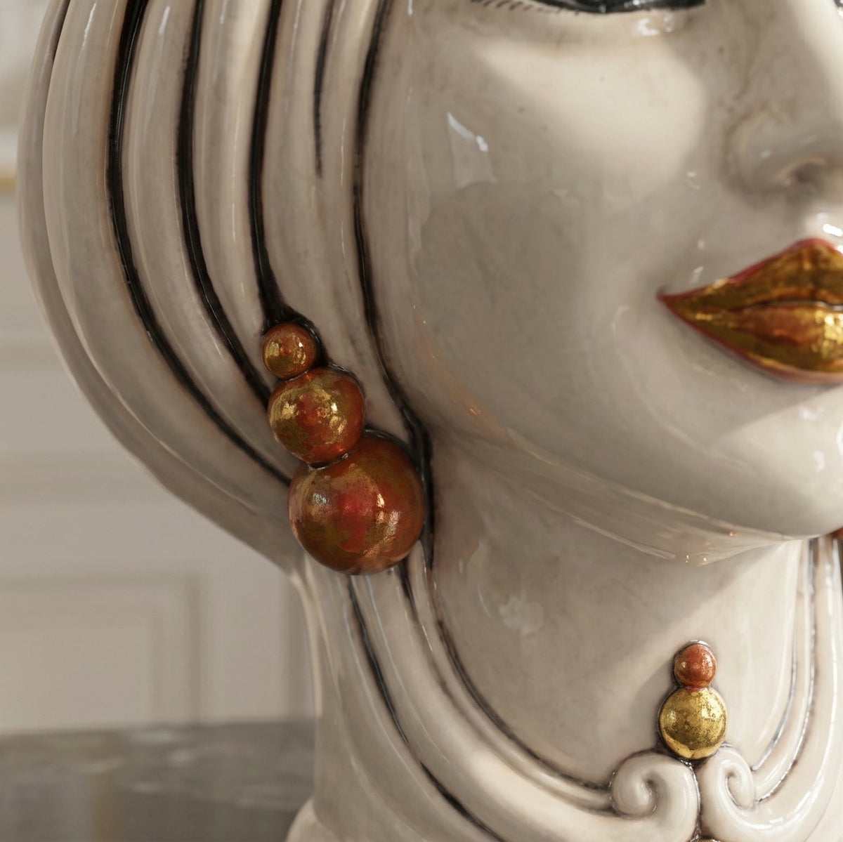 Detail der weiblichen Testa di Moro: Perlenohrring und goldene Lippen