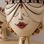 Detail of the female Zahira head with flowers: red lips, gold earrings and amber beads
