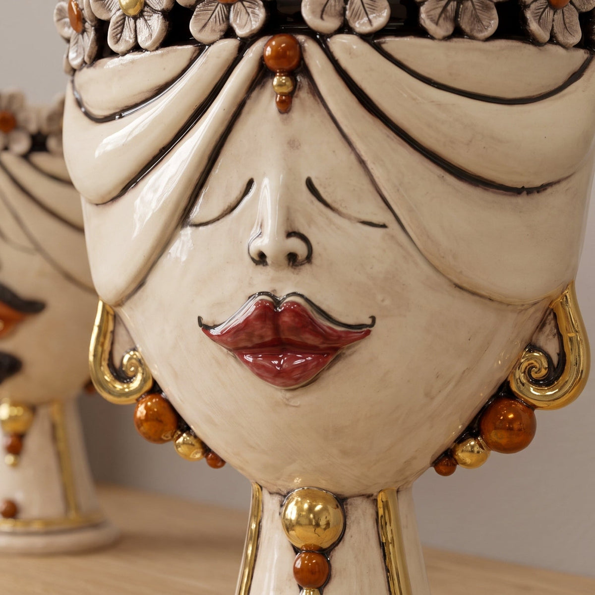 Detail of the female Zahira head with flowers: red lips, gold earrings and amber beads