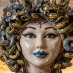 Close-up of the Medusa head with flowers: green eyes, blue diadem and blue lips