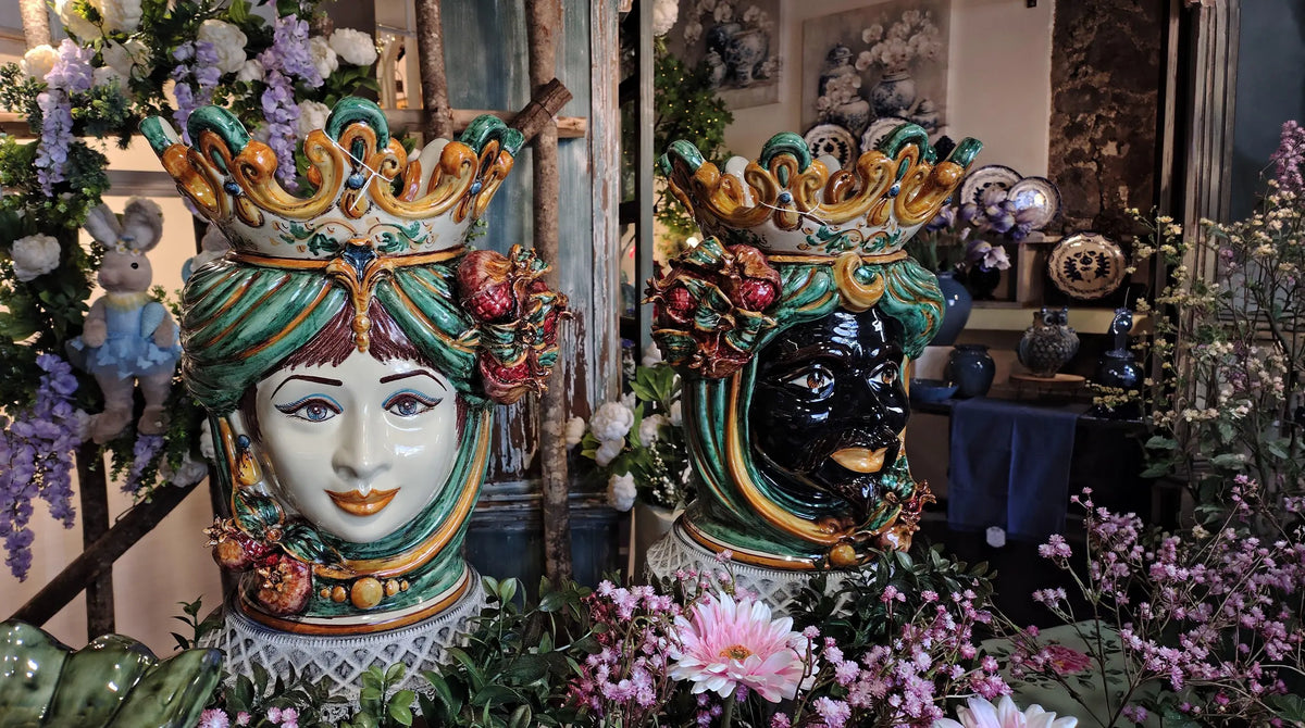 Pair of green and gold Teste di Moro with crowns, woman and dark-faced man, among flowers and plants
