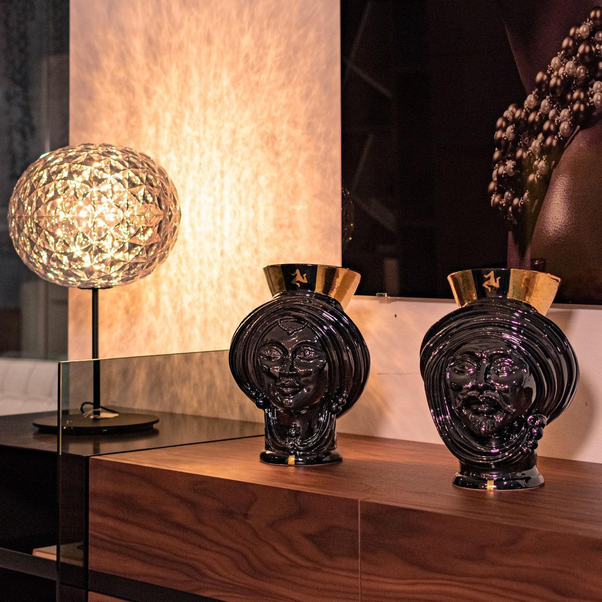 Paar Teste di Moro Black and Gold auf einem Holzsideboard neben einer Designerlampe