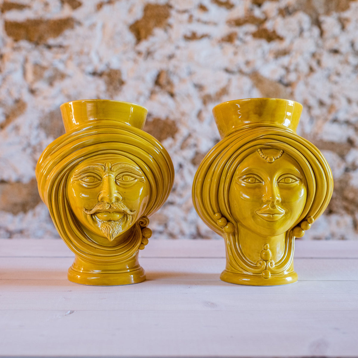 Mustard Teste di Moro, man and woman, side by side on a light wooden surface