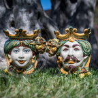 Handmade Caltagirone ceramics: colourful regal faces on grass, traditional Sicilian art