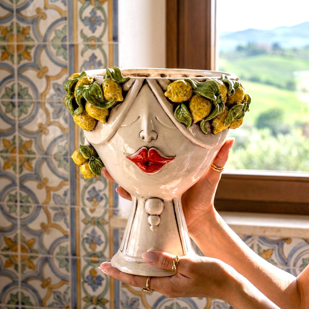 Female Zahira head with lemons held in two hands, against a wall of Sicilian majolica tiles