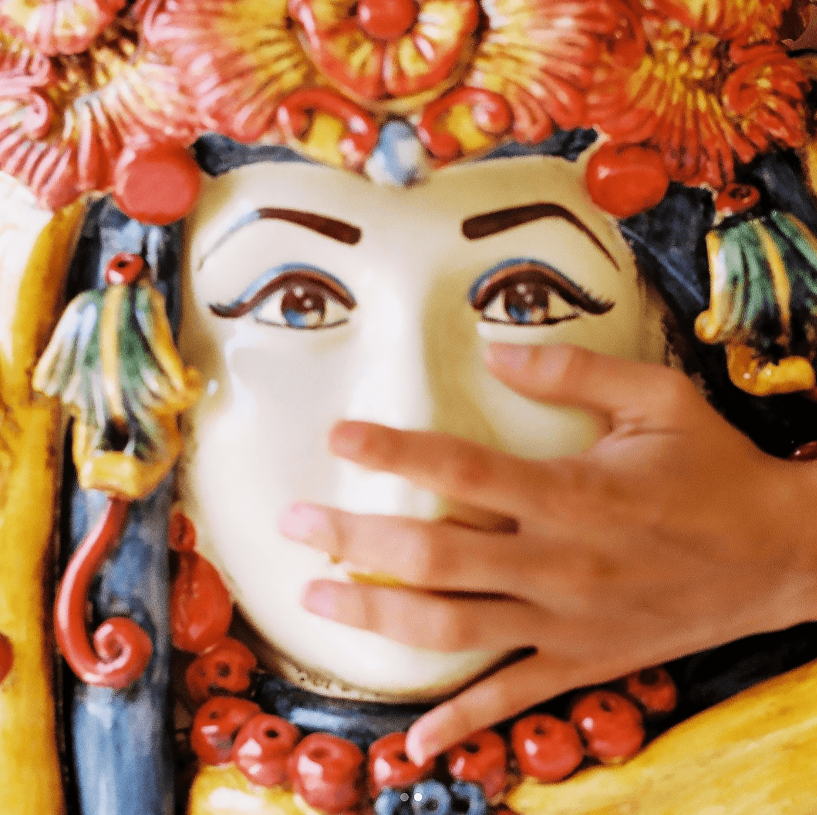 A hand touching the face of the 50 cm Testa di Moro with turban, hand-painted red and orange flowers