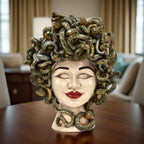 Testa Medusa Sognia a occhi chiusi in madreperla antichizzata, su un tavolo in legno